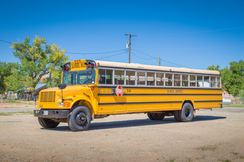 Panorama view of classic traditional yellow school bus standing on a parking lot on a beautiful sunny day with blue sky in summer in North America