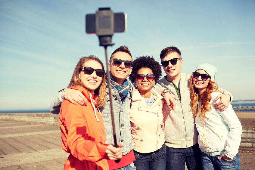 smiling friends taking selfie with smartphone on group travel trip