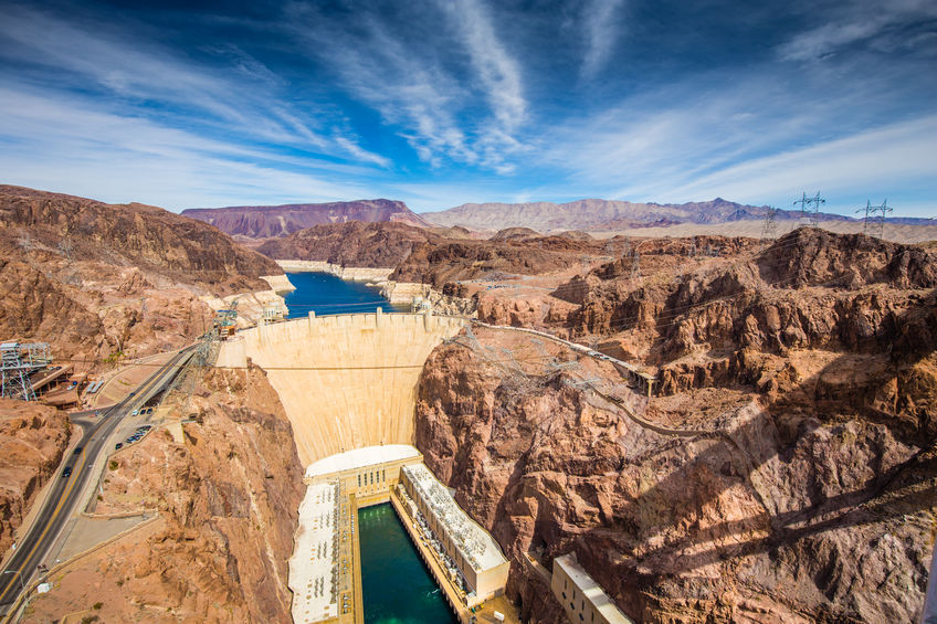Aerial wide angle view of famous Hoover Dam, a major tourist attraction located on the border between the states of Nevada and Arizona, on a beautiful sunny day with blue sky and clouds in summer, USA