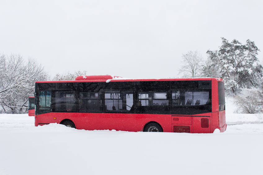 Red city bus parked in winter time in heavy snow
