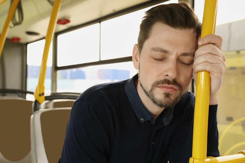 Man suffering from motion sickness while sitting in public transport.